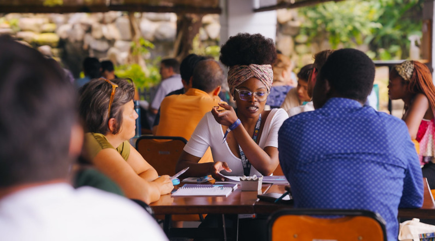 Photo of an African student and other students discussing around a table