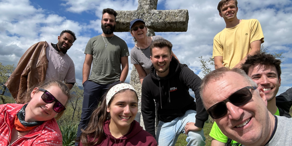 Network members gather around a stone cross on a hillside